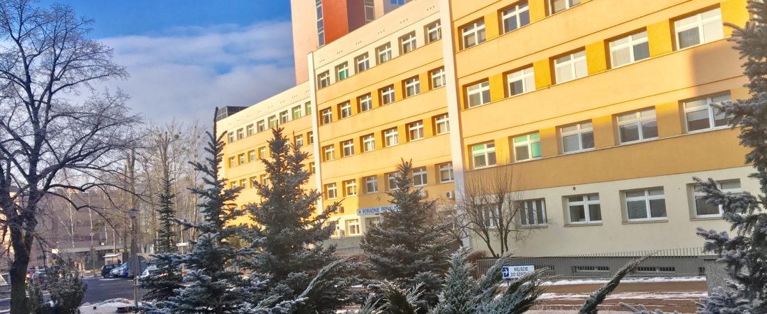 Widok szpitala z zewnątrz w zimowej scenerii.