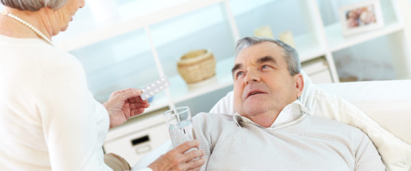 Starsza osoba podająca lek drugiej osobie